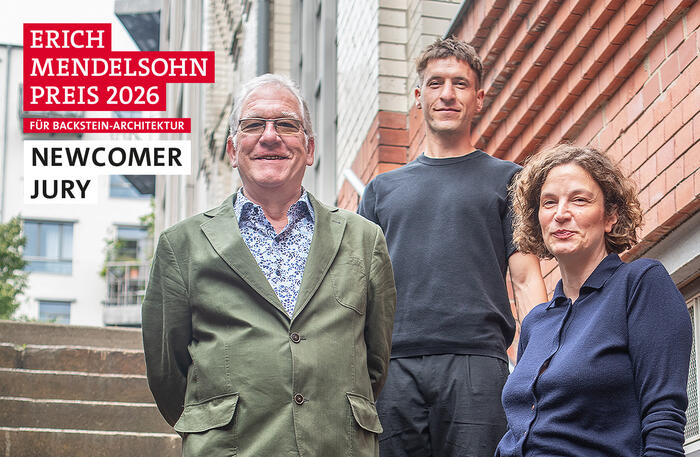 Drei Personen vor einem Backsteingebäude mit der Aufschrift Erich Mendelsohn Preis 2026 für Backstein-Architektur Newcomer Jury