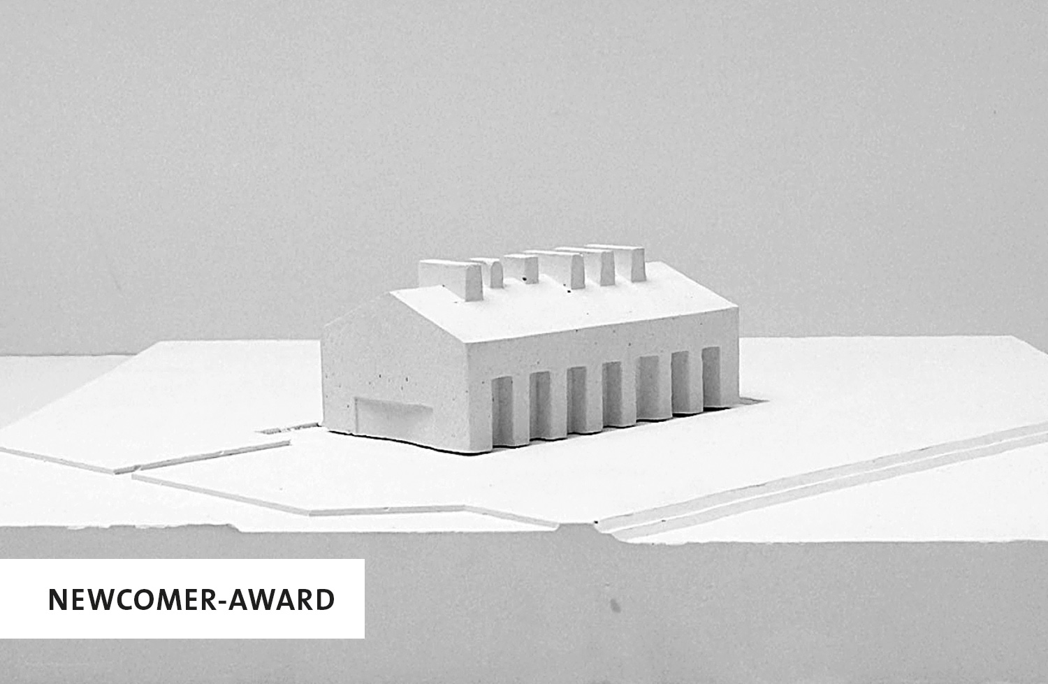 Ein weißes Modell von einem Gebäude, unten links die Aufschrift: Newcomer-Award