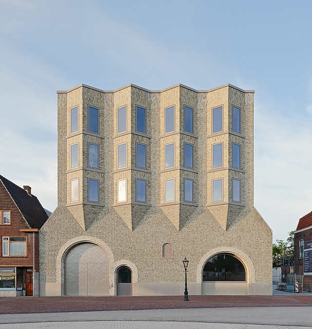 Ein großes graues Backstein-Gebäude, das Museum De Lakenhal, vor einem blauen Himmel.